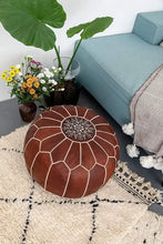 Load image into Gallery viewer, Brown leather pouf with geometric design on a patterned rug, next to a teal sofa and potted plants.